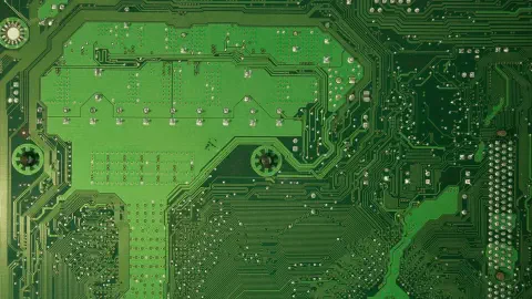 close-up detalhado de uma placa de circuito impresso (PCB) de cor verde. A superfície é coberta por uma com