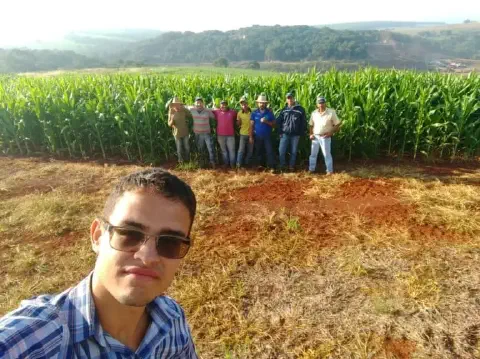 momento de confraternização e trabalho no campo. Em primeiro plano, um jovem de camisa xadrez e óculos de