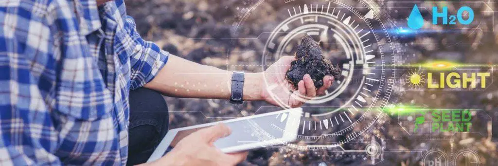 agricultor ou agrônomo em um campo de terra arada, agachado para analisar uma amostra de solo que segura