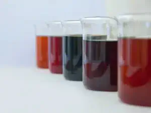 uma fileira de cinco béqueres de vidro, alinhados em perspectiva sobre uma superfície branca e limpa, remetend