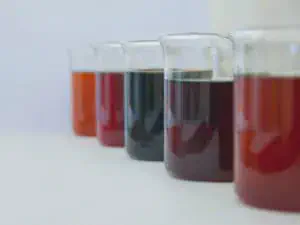 uma fileira de cinco béqueres de vidro, alinhados em perspectiva sobre uma superfície branca e limpa, remetend