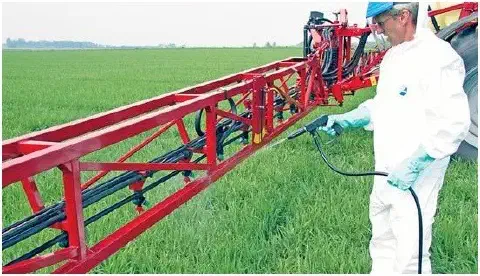 agricultor profissionalmente equipado em meio a uma lavoura verdejante. O trabalhador veste um traje de p