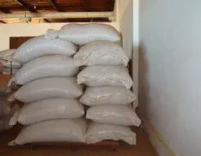 duas pilhas de sacos brancos, provavelmente de polipropileno, cheios e empilhados sobre um palete de madeira.