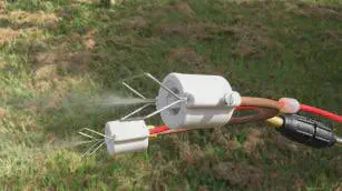 Bico de Pulverização Agrícola: Tecnologia e Eficiência close-up de um bico de pulverização duplo, de aspecto técnico, em plena operação sobre um gramado. O dispos