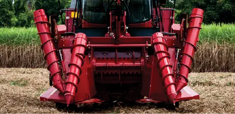 a parte frontal de uma colhedora de cana-de-açúcar em plena operação no campo. Em destaque, estão os divisores