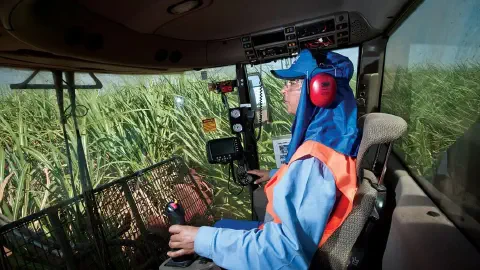 perspectiva interna da cabine de uma moderna colheitadeira agrícola, com um operador focado em seu trabalh