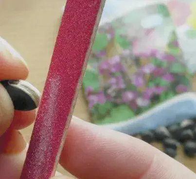 close-up de uma pessoa realizando a escarificação de uma semente de girassol. A mão segura a semente, que t