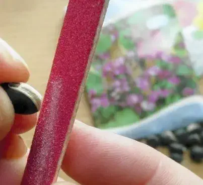 close-up de uma pessoa realizando a escarificação de uma semente de girassol. A mão segura a semente, que t