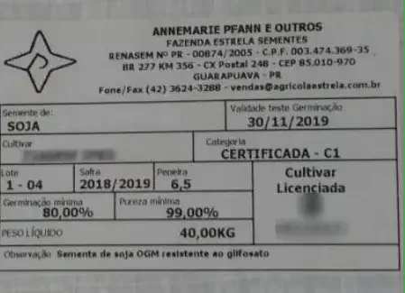 close-up da etiqueta de uma saca de sementes de soja. A etiqueta, de fundo branco com texto em preto e deta