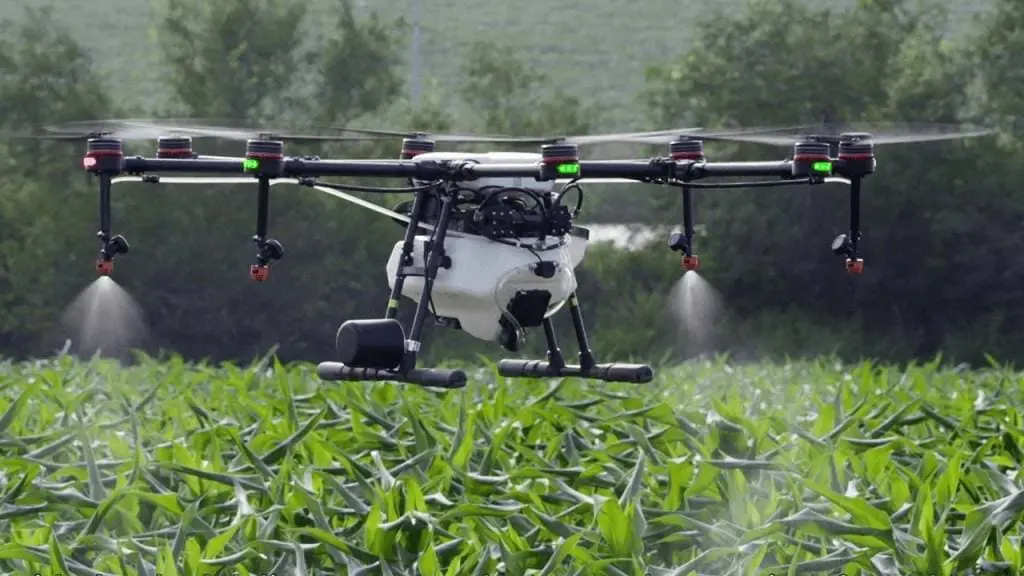 drone agrícola de grande porte, um octocóptero, em plena operação sobre uma lavoura de milho. O equipamento