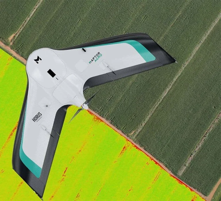 drone de asa fixa, modelo Maptor Agro da Horus, sobrevoando uma extensa área de lavoura. A composição visua