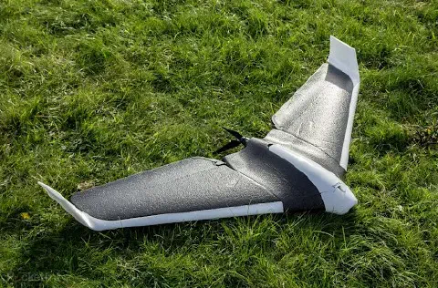 drone de asa fixa, provavelmente um modelo eBee, pousado sobre um gramado verde. O equipamento, com design