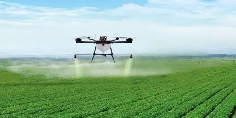 drone agrícola de grande porte em pleno voo sobre uma extensa lavoura verde, com as culturas plantadas em f