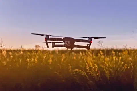 drone quadricóptero moderno em voo baixo sobre uma lavoura com flores amarelas, provavelmente colza ou um