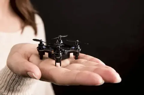 close-up da mão de uma pessoa segurando um pequeno drone preto, também conhecido como mini drone ou nano dr
