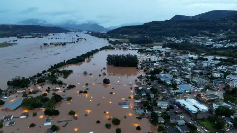 vista aérea desoladora de uma cidade severamente inundada, provavelmente no sul do Brasil, dado o relevo. Um r