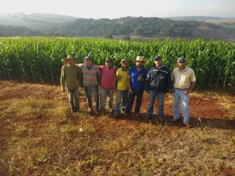 grupo de sete agricultores posando juntos, com um semblante de satisfação e orgulho, em frente a uma exte