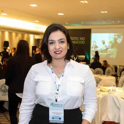mulher em um ambiente de evento corporativo, provavelmente uma conferência ou seminário focado no agrone