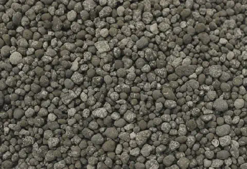 uma visão em close-up de um amontoado de fertilizante granulado. Os grânulos são pequenos, com formatos irregu