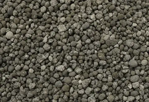 uma visão em close-up de um amontoado de fertilizante granulado. Os grânulos são pequenos, com formatos irregu