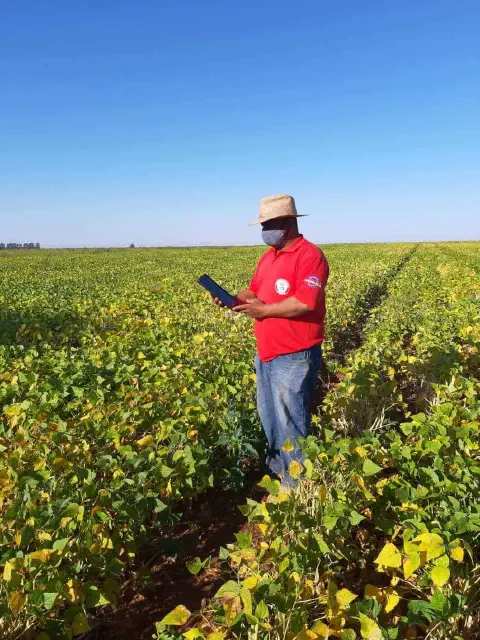 profissional do agronegócio, possivelmente um agrônomo ou produtor rural, em meio a uma extensa lavoura d