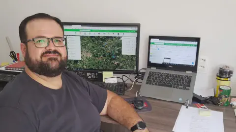 profissional do agronegócio, possivelmente um produtor rural ou consultor, em seu escritório, utilizando