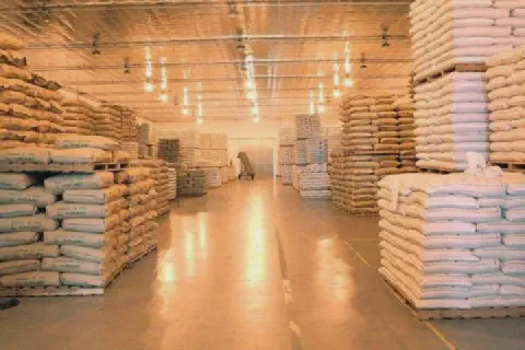 o interior de um amplo e bem iluminado armazém agrícola, meticulosamente organizado. Corredores extensos separ