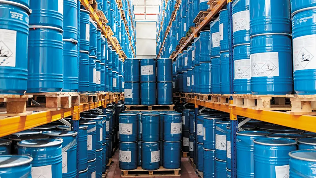 grande depósito industrial, meticulosamente organizado com altas prateleiras de estocagem. Inúmeros barris