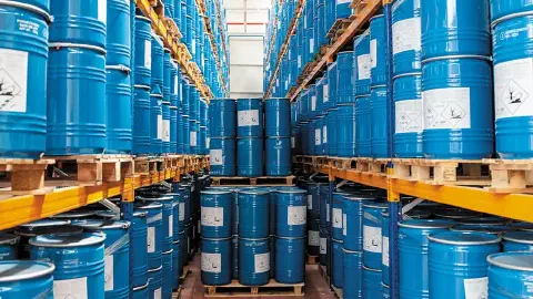 grande depósito industrial, meticulosamente organizado com altas prateleiras de estocagem. Inúmeros barris