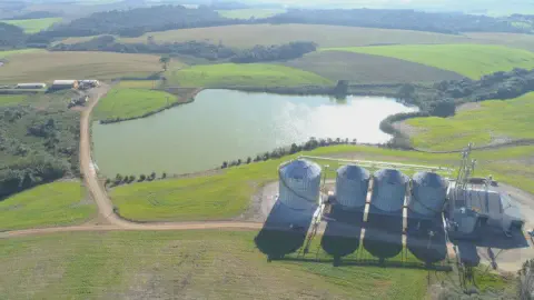uma vista aérea panorâmica de uma propriedade rural moderna e bem estruturada. Em primeiro plano, destaca-se u