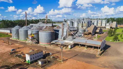 Vista aérea de um grande complexo agroindustrial destinado à armazenagem e beneficiamento de grãos. A imagem exibe múltiplos