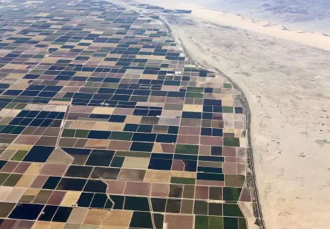 uma impressionante vista aérea que contrasta drasticamente uma vasta área de agricultura irrigada com um deser
