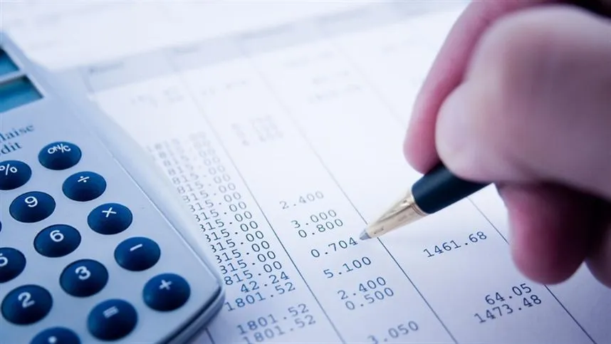 Pessoa segurando uma caneta em meio a papéis com resultados financeira da fazenda