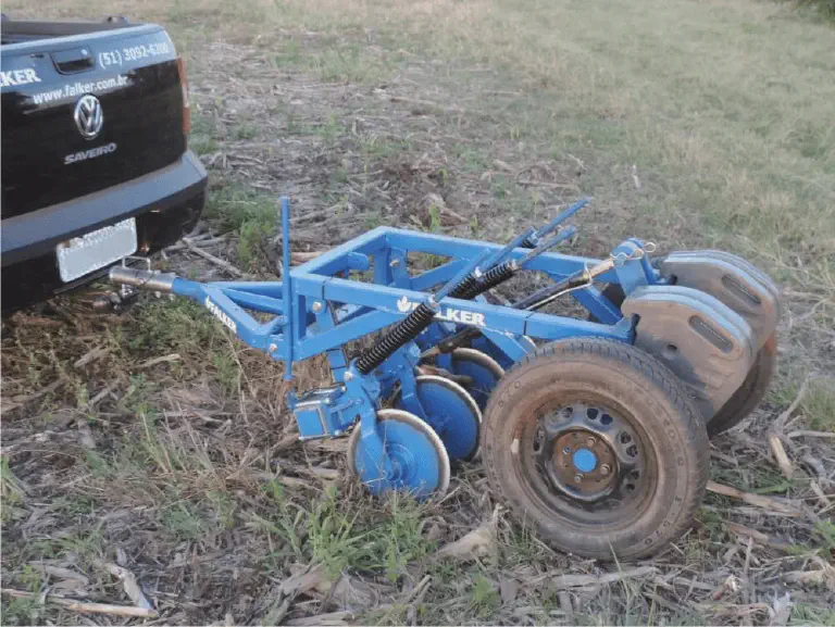 Implemento Agrícola para Plantio Direto Falker implemento agrícola de cor azul, especificamente uma plantadeira ou semeadora, da marca Falker, engatado na