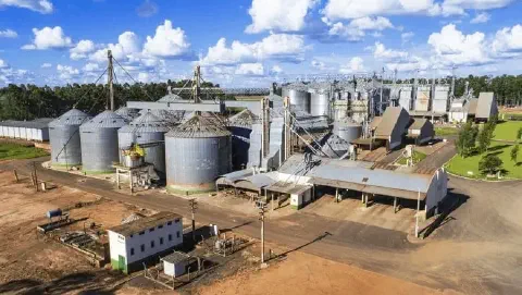 uma vista aérea de um grande complexo agroindustrial, especializado em armazenamento e processamento de grãos.