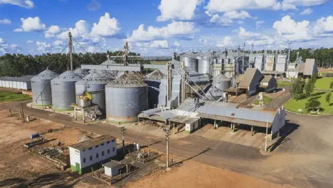 uma vista aérea de um grande complexo agroindustrial, especializado em armazenamento e processamento de grãos.