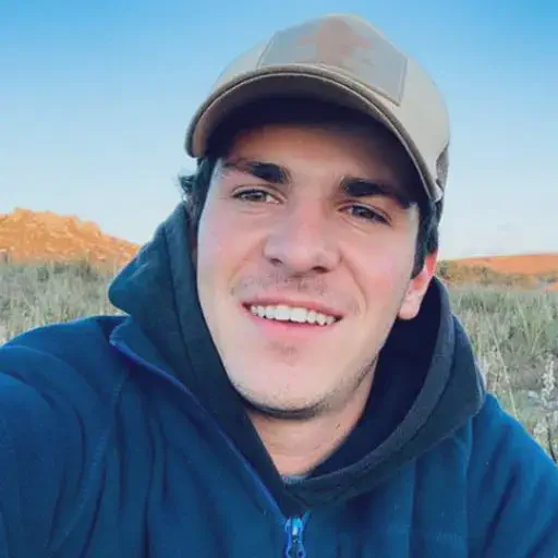 Jovem produtor rural: sucesso na gestão da fazenda retrato em close-up de um jovem, possivelmente um produtor rural ou agrônomo, em um ambiente externo. Ele sorri