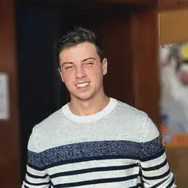 Jovem profissional do agronegócio | Cliente Aegro retrato em close-up de um jovem adulto do sexo masculino, sorrindo de forma amigável e confiante para a câmera.