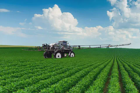 pulverizador autopropelido moderno em plena operação numa vasta lavoura de soja. O maquinário, de grande po