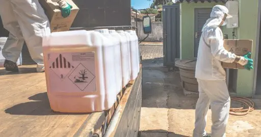 imagem retrata dois trabalhadores rurais devidamente equipados com Equipamentos de Proteção Individual (EPIs) completos, in