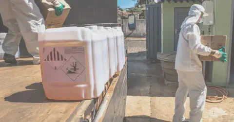 imagem retrata dois trabalhadores rurais devidamente equipados com Equipamentos de Proteção Individual (EPIs) completos, in