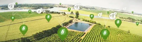 uma vista aérea panorâmica de uma vasta área rural, mostrando diversas plantações, um reservatório de água e u