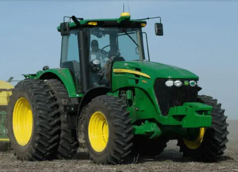 trator agrícola moderno, da marca John Deere, modelo 7200J, em plena operação num campo preparado para o pl