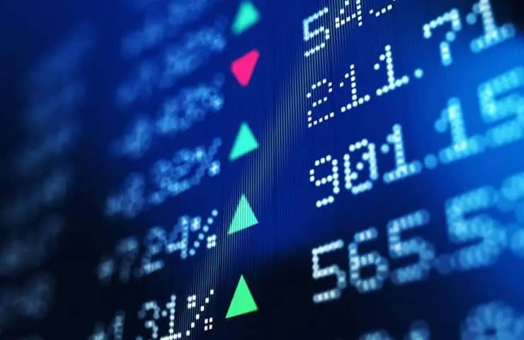 close-up de uma tela digital com dados do mercado financeiro, apresentada em um ângulo dinâmico. O fundo é