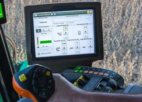 o interior da cabine de uma colheitadeira moderna, focando na interface tecnológica utilizada pelo operador. E