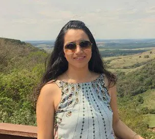 Mulher no Agro: Sucesso com Gestão de Fazendas o retrato de uma mulher jovem, de cabelos escuros e longos, usando óculos de sol e sorrindo para a câmera. Ela