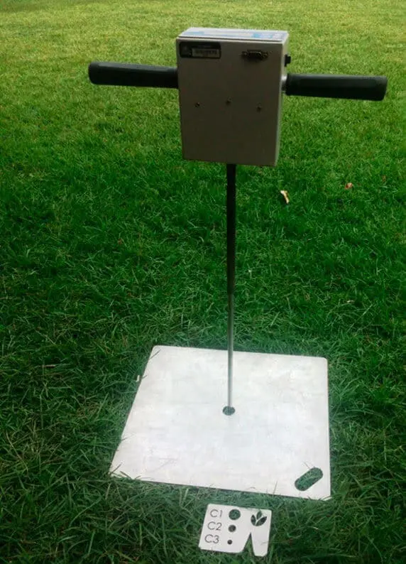 equipamento técnico para análise de solo, posicionado sobre um gramado verde. O aparelho, provavelmente um