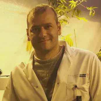 Pesquisador Agrícola em Laboratório de Biotecnologia retrato de um homem de meia-idade, caucasiano, com cabelo curto e castanho, olhando diretamente para a câm