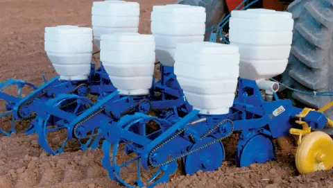 uma plantadeira agrícola, também conhecida como semeadora, em um campo de terra preparada para o plantio. O eq