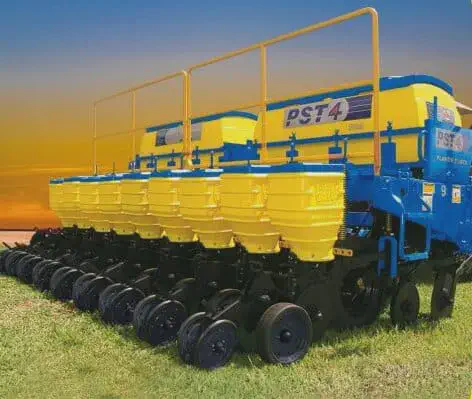 uma plantadeira agrícola de grande porte, modelo PST4, em um campo com grama verde sob um céu de fim de tarde